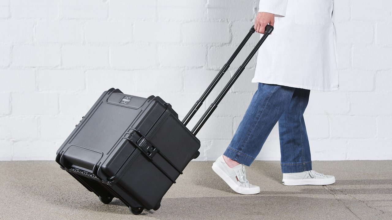 一个穿白大褂的人拉着一个带加长把手的提箱。